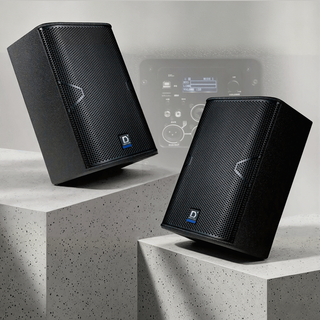 ront and back view of a Digmex Audio DMX A-One-Pro powered loudspeaker. The front features a black metal grille with a "D" logo, while the back shows a built-in digital mixer, LCD screen, and various audio input/output ports.